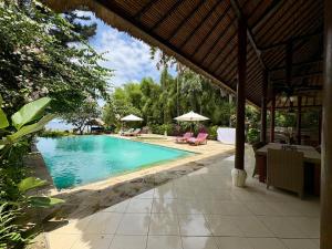 une piscine avec chaises et parasols dans une cour dans l'établissement Beachfront Villa Nirwana with Private Jacuzzi, à Pengastulan