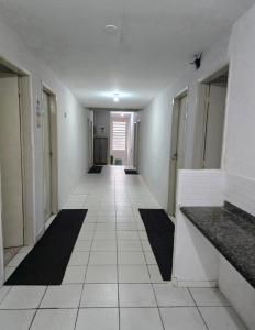 un corridoio con pavimenti in piastrelle bianche e un lungo corridoio di MarBelo Bertioga Apartamentos e Suítes a Bertioga