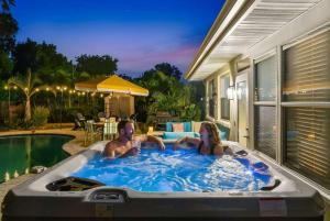a man and a woman sitting in a hot tub at Resort Style Backyard Pool Hot Tub Games in Seminole