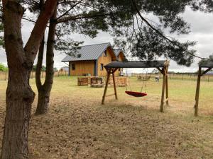 a swing in front of a tree with a house at Leśny zakątek in Wisełka