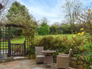 een patio met een tafel en stoelen in een tuin bij Lower Axford Cottage in Callington