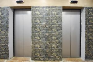 a row of three elevator doors in a stone wall at Hotel O by OYO Crown Aura in kolkata +27 photos
