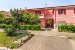 un banc vert assis devant un bâtiment rose dans l'établissement L'Aurora Viola, à Carbonia