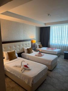 una camera d'albergo con due letti con asciugamani sopra di Barden Hotel&Spa a Siirt