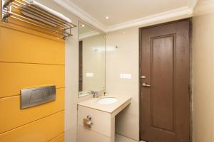 a bathroom with a sink and a mirror and a door at The Senate Hotel By Addon Group in Cochin +26 photos