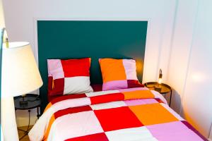 een kleurrijk bed met kleurrijke kussens in een kamer bij La Petite Perle de Noisy in Noisy-le-Grand +11 foto's