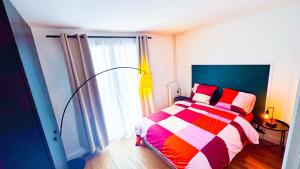 een slaapkamer met een kleurrijk bed en een raam bij La Petite Perle de Noisy in Noisy-le-Grand