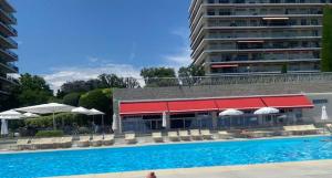 a swimming pool next to a building with a red roof at NICE BAIE DES ANGES in Nice