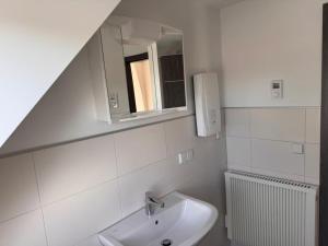 un bagno bianco con lavandino e specchio di NEU! Ferienwohnung Elsteraue DG oben a Meuselwitz