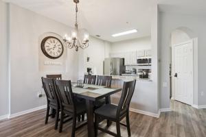 a dining room with a table and chairs and a clock at 3BR Windsor Hills Condo Water Park and Skeeball Near Disney No Resort Fees in Orlando