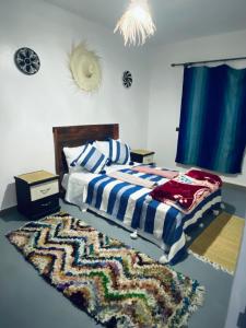 a bedroom with a bed and a rug on the floor at Momo Surf Housse in Wassane
