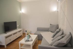 een woonkamer met een bank en een tv bij La Casa Rosa in Lefkada