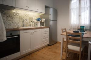 een keuken met witte kasten, een tafel en een koelkast bij La Casa Rosa in Lefkada