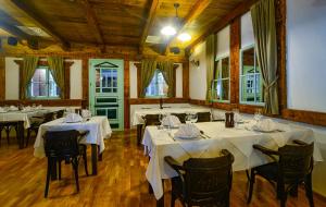 a restaurant with white tables and chairs and windows at Hotel Risnjak in Delnice