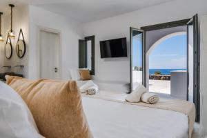 a bedroom with a large bed with a view of the ocean at The Amethyst Exclusive Suites Oia in Oia