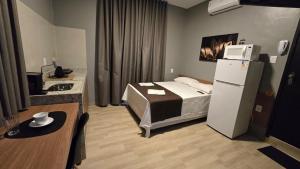 a hotel room with a bed and a refrigerator at FLATS MELO unimontes in Montes Claros