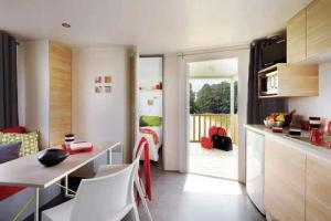 a kitchen with a table and chairs in a room at ZEcamping 3 étoiles pet friendly avec piscine et pataugeoire in Les Assions