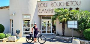 a woman riding a bike in front of a store at ZEcamping 3 étoiles pet friendly avec piscine et pataugeoire in Les Assions