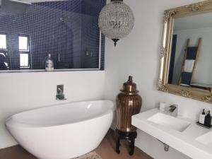 鲸湾港雷兹旅馆的一间带大型白色浴缸和镜子的浴室 更多94张照片