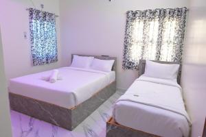 ein Schlafzimmer mit zwei Betten und zwei Fenstern in der Unterkunft The Joie Luxury in Puducherry