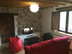 a living room with a red couch and a tv at La Casuca in Rasines