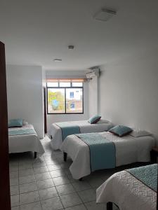 ein Zimmer mit drei Betten und einem Fenster in der Unterkunft La Isla Del Descanso in Puerto Villamil