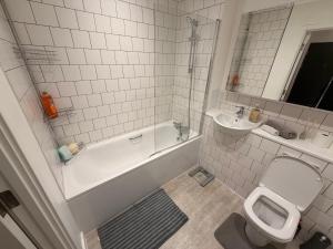 a bathroom with a tub and a toilet and a sink at HRF Barking Apartments in Barking +18 photos