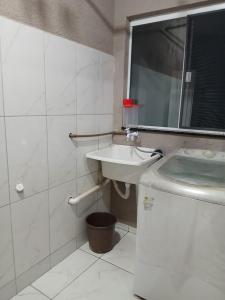 een witte badkamer met een wastafel en een spiegel bij Casa aconchegante e familiar em Matinhos in Matinhos