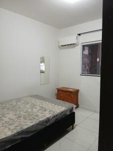 een slaapkamer met een bed, een ladekast en een raam bij Casa aconchegante e familiar em Matinhos in Matinhos