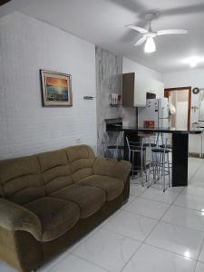 een woonkamer met een bruine bank en een keuken bij Casa aconchegante e familiar em Matinhos in Matinhos