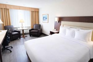 a hotel room with a large bed and two chairs at Quality Inn & Suites in Gatineau