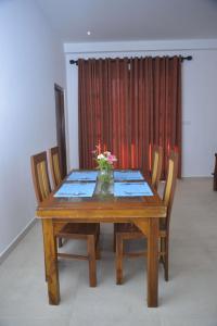 une table en bois avec des chaises et un vase de fleurs dessus dans l'établissement Blue Horizon Villa - Rathgama, à Ratgama Hegoda