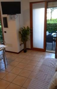 un soggiorno con una pianta in vaso e una TV di Villetta Serenity presso Residence ai Salici a Caorle Altre 9 foto