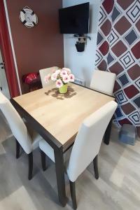 een houten tafel met witte stoelen en een vaas met bloemen erop bij Mobile Home 127 Bois Dormant in Saint-Jean-de-Monts +2 foto's