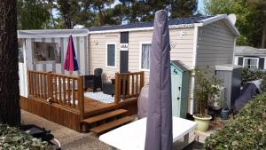 een tiny house met een terras en een veranda bij Mobile Home 127 Bois Dormant in Saint-Jean-de-Monts