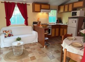 a living room with a white couch and a kitchen at Mobil Home sans vis a vis in Saint-Georges-de-Didonne