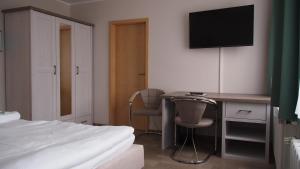 ein Schlafzimmer mit einem Bett und einem Schreibtisch mit einem Fernseher in der Unterkunft Pension Clara in Tanneberg