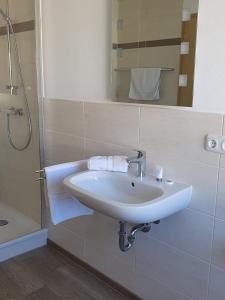 ein weißes Waschbecken in einem Badezimmer mit Dusche in der Unterkunft Pension Clara in Tanneberg
