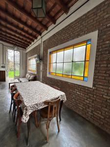 una sala da pranzo con tavolo e sedie e un muro di mattoni di Casa Casona Las Toscas a Miramar