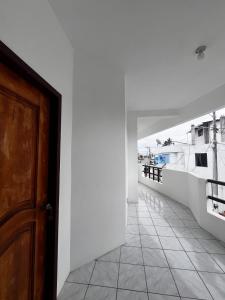 einen Flur mit einer Holztür und einer weißen Wand in der Unterkunft La Isla Del Descanso in Puerto Villamil