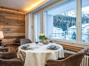 een eetkamer met een tafel en stoelen en een groot raam bij Apartment Chesa Fleury by Interhome in St. Moritz