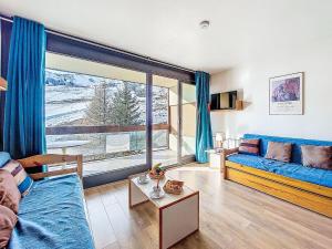 een woonkamer met een bank en een groot raam bij Studio Cosmos-1 by Interhome in Le Corbier