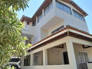a white house with trees in front of it at Hostel Peró Cabo Frio in Cabo Frio