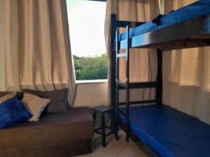 a bedroom with two bunk beds and a couch at Hostel Peró Cabo Frio in Cabo Frio