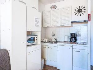une cuisine blanche avec des armoires blanches et un micro-ondes dans l'établissement Studio Les Hauts du Port-1 by Interhome, à Saint-Cyr-sur-Mer