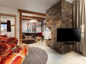 a living room with a stone wall with a flat screen tv at Apartment Mountain Resort C15 by Interhome in Kaprun +15 photos