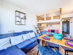 ein Wohnzimmer mit einem blauen Sofa und einem Tisch in der Unterkunft Studio Soyouz Vanguard-100 by Interhome in Le Corbier