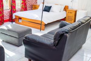 ein Schlafzimmer mit einem Bett, einer Couch und einem Stuhl in der Unterkunft Alfords Villa 