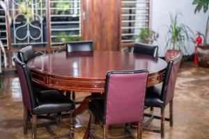 ein Holztisch mit vier Stühlen um ihn herum in der Unterkunft Alfords Villa 