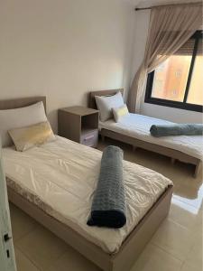 Un dormitorio con dos camas y una ventana. en Résidence Al Hayat Agadir, en Aourir